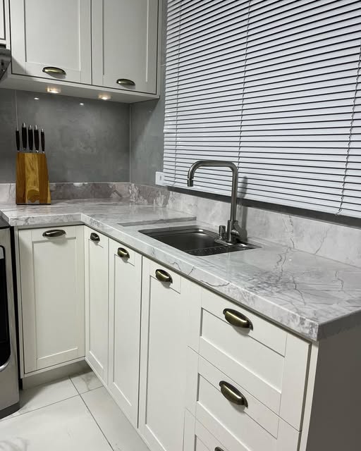 Cozinha branca com bancada em mármore e torneira inox